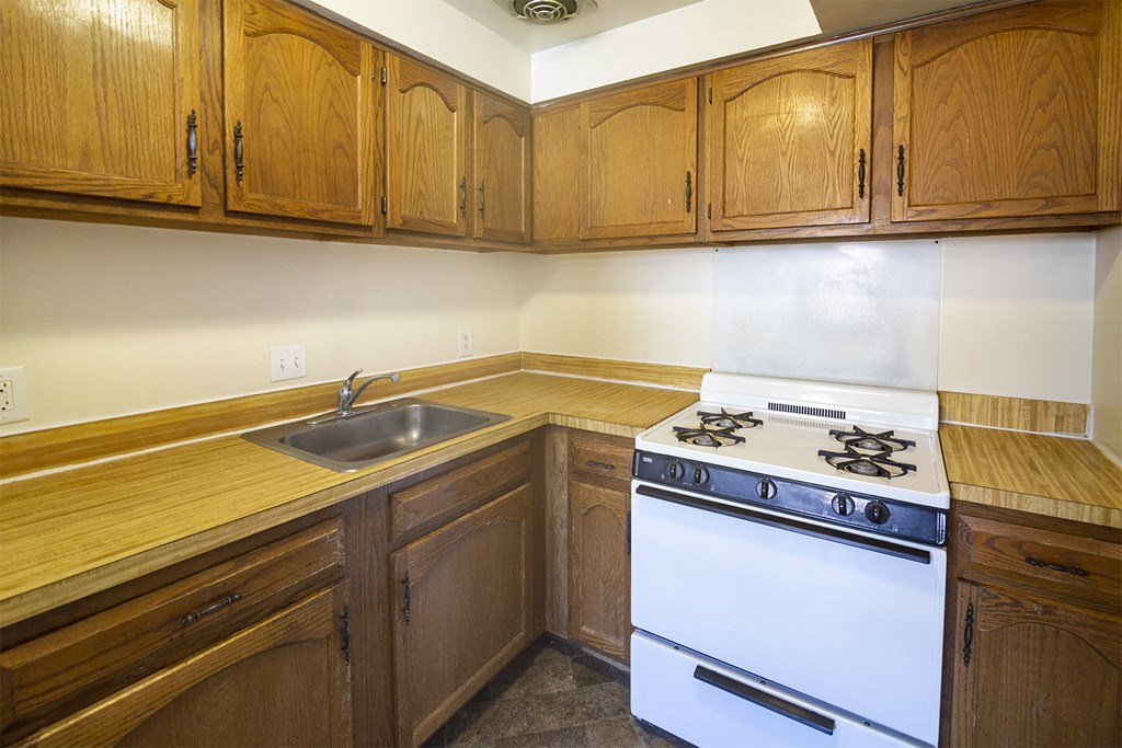 a kitchen with a stove and sink and wooden cabinets