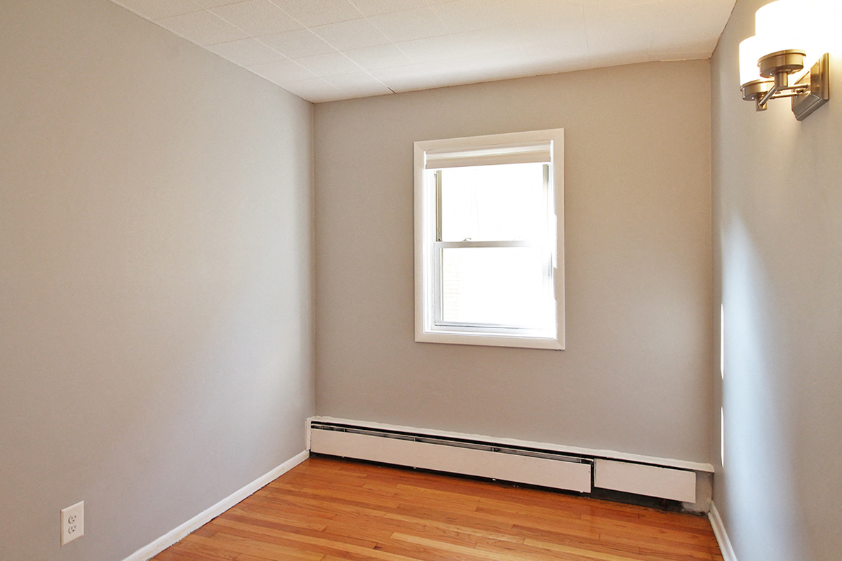 an empty room with a window and a wood floor