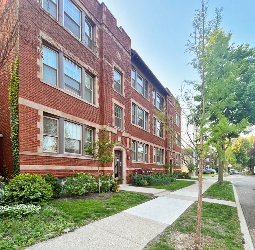 A red brick building with a tree in front of it.
