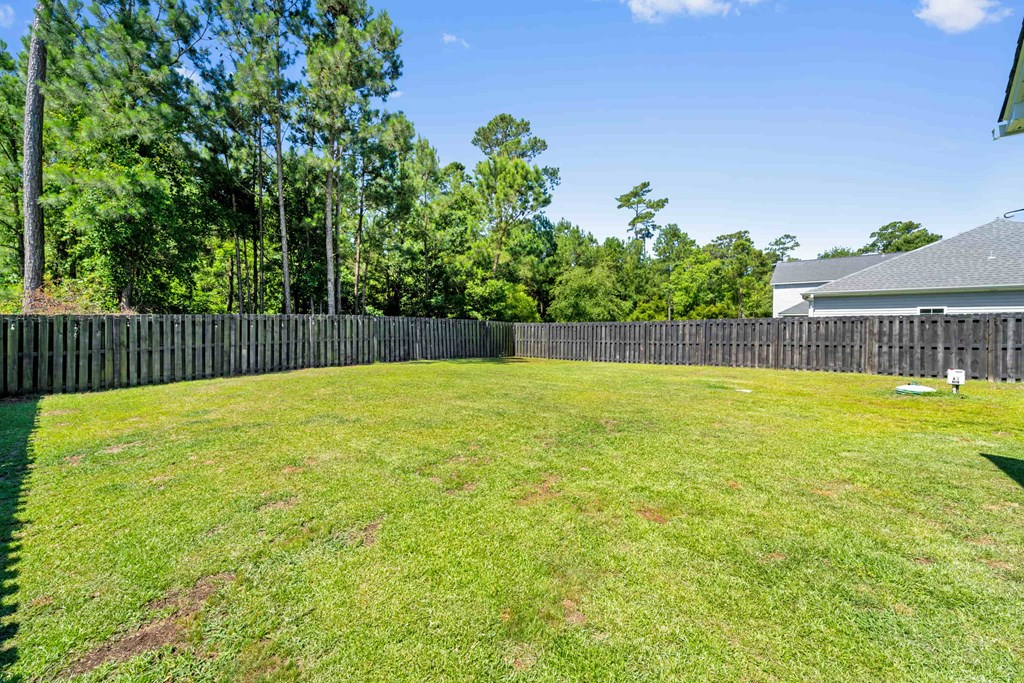 a yard with a fence and a house on the other side