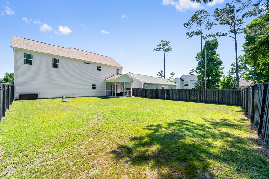 a backyard with a white house and a fence