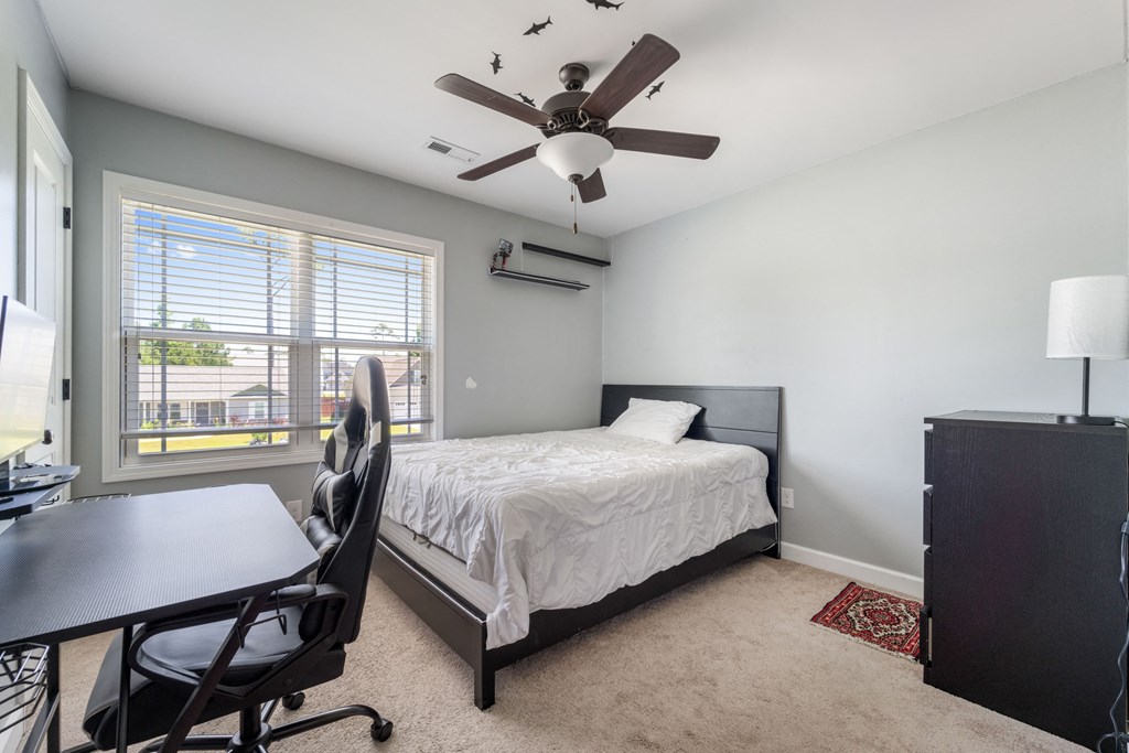 a bedroom with a bed and a ceiling fan and a desk
