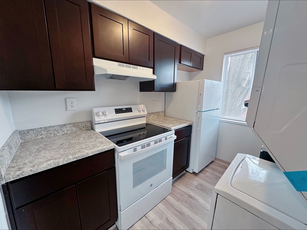 A kitchen with brown cabinets and white appliances.