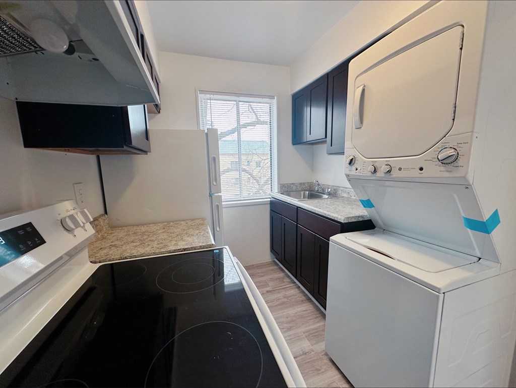 A kitchen with a black stove top oven and a white refrigerator.