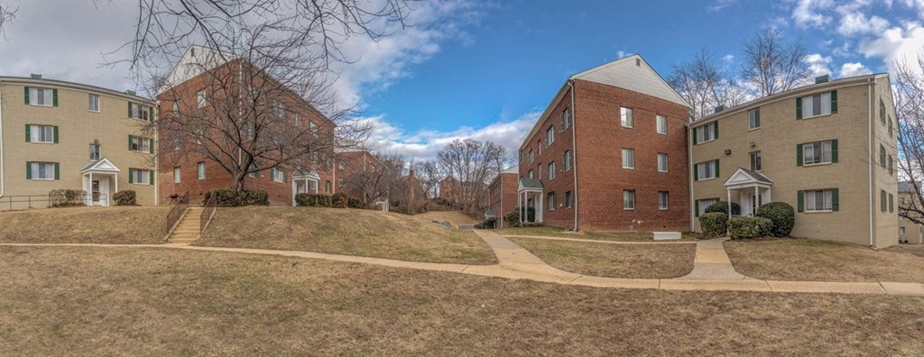A row of apartment buildings with a grassy area in front.