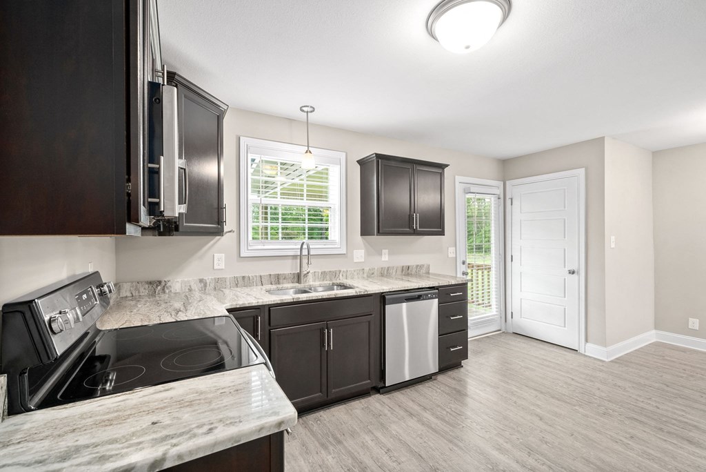 a kitchen with black cabinets and a sink and a window