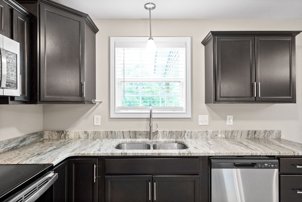a kitchen with black cabinets and granite counter tops and a window