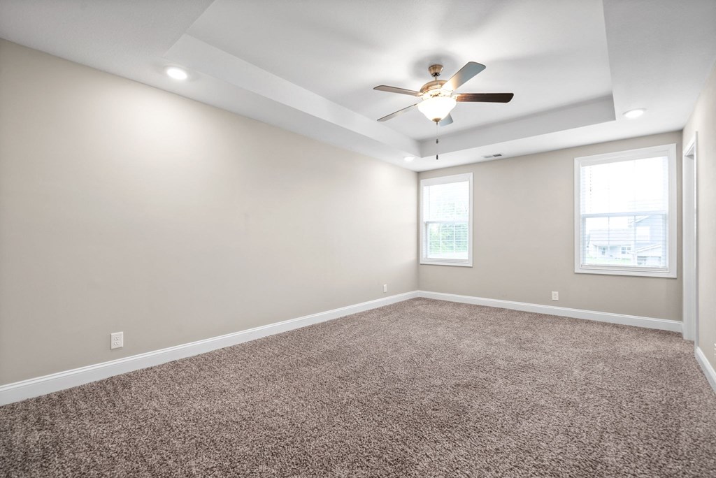 an empty room with carpet and a ceiling fan