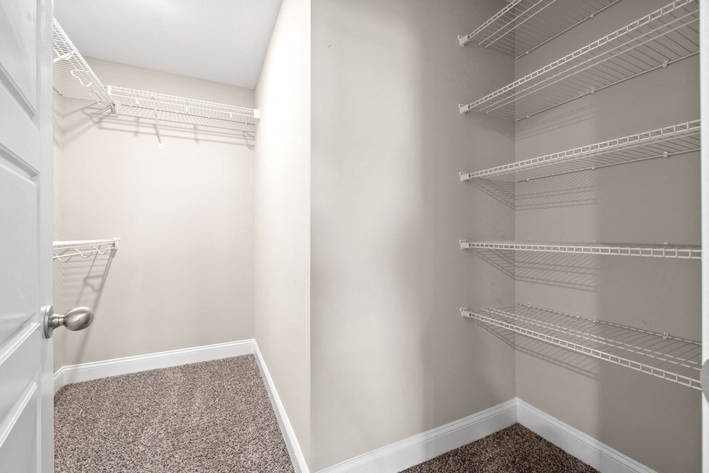 the closet in a bedroom with shelves and a door