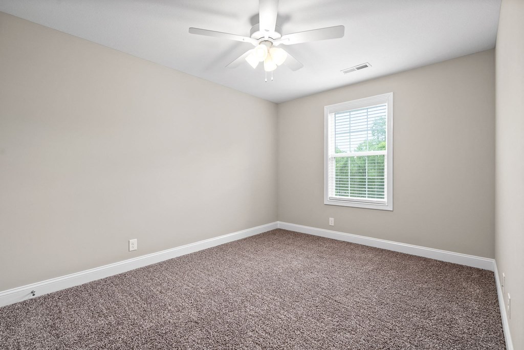 an empty bedroom with a ceiling fan and a window