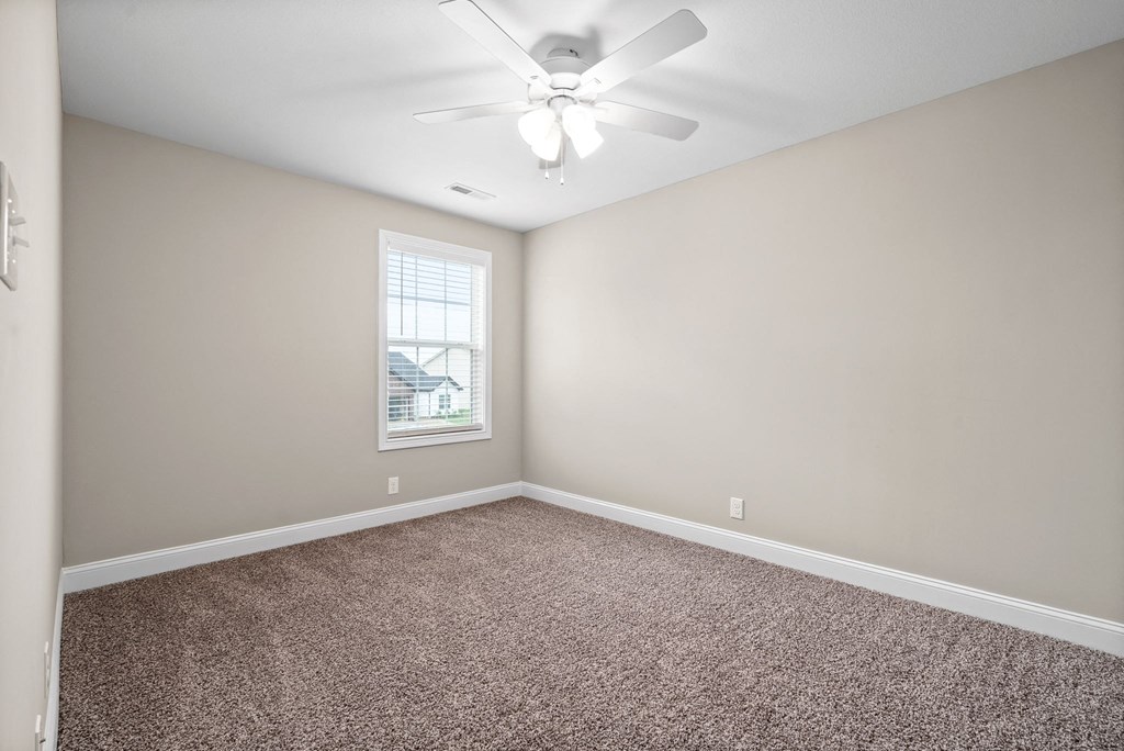 an empty room with carpet and a ceiling fan