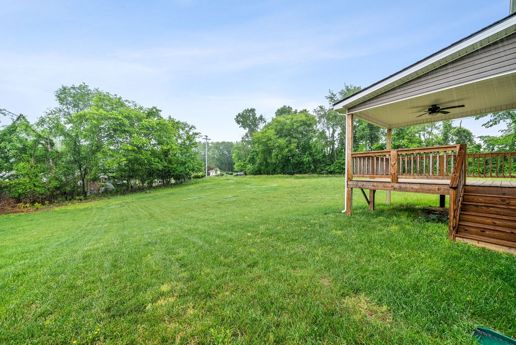 a backyard with a deck and a house with a lawn and trees