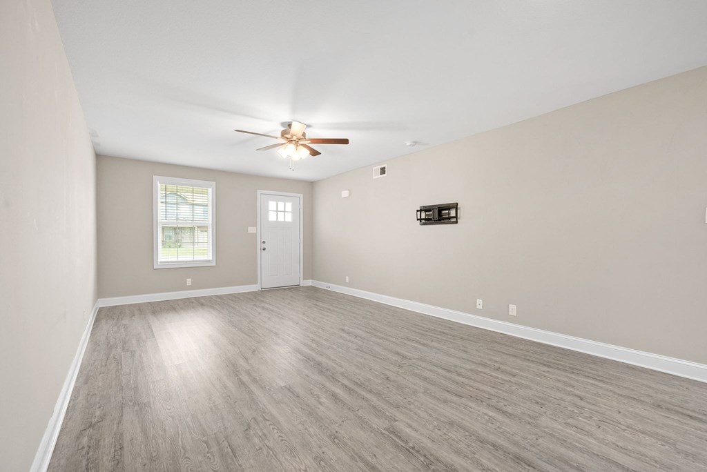 an empty living room with a ceiling fan and a window