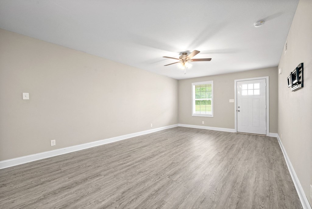 an empty living room with a ceiling fan and a door