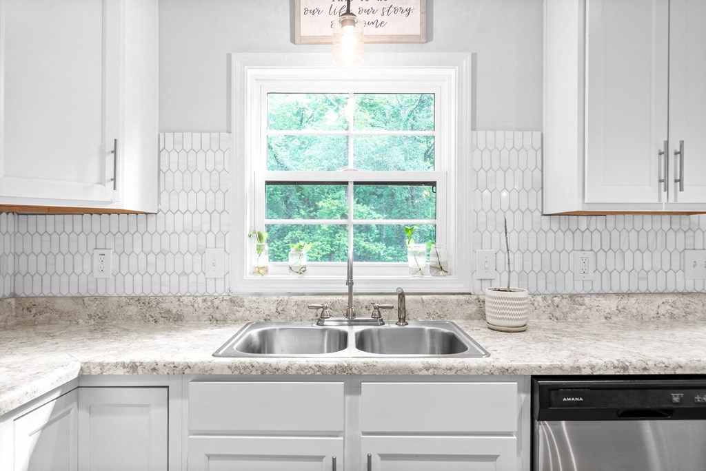 a white kitchen with a sink and a window