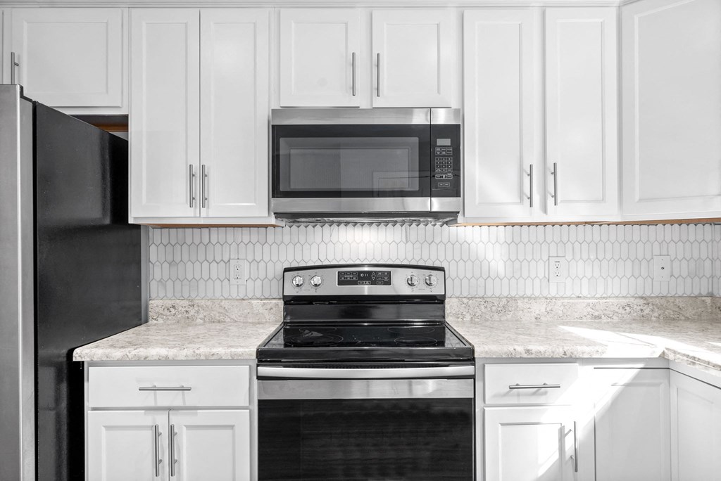 a kitchen with white cabinets and a stove and a microwave