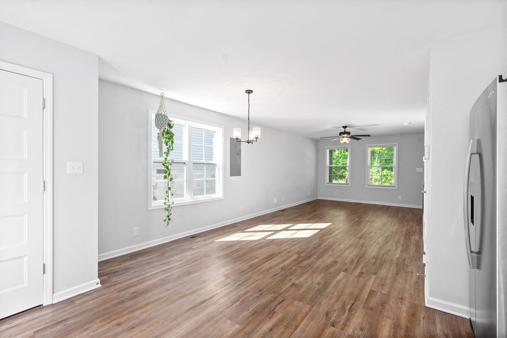 the living room and dining room of a new home with wood floors and white walls