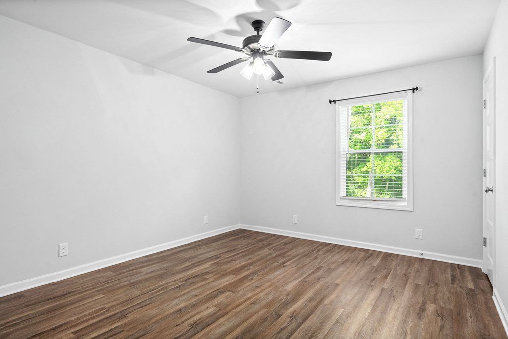 an empty room with hardwood floors and a ceiling fan