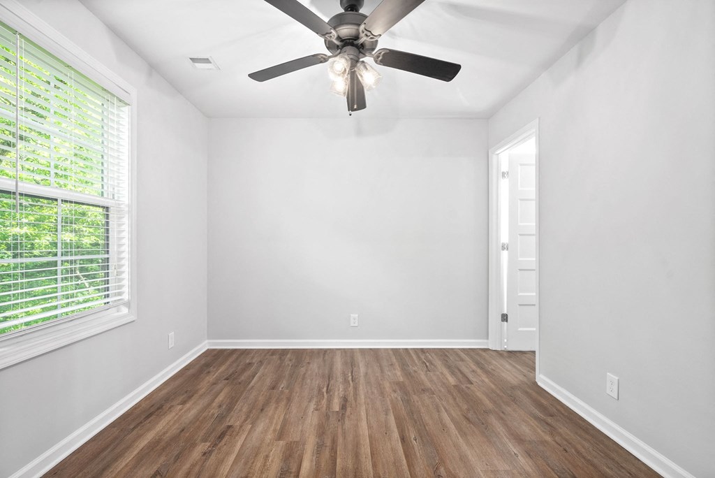 an empty living room with a ceiling fan and a window