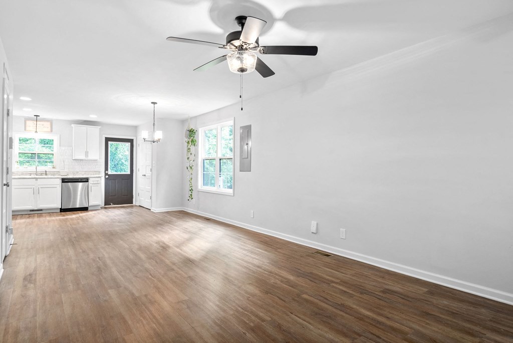 an empty living room with a ceiling fan and a kitchen