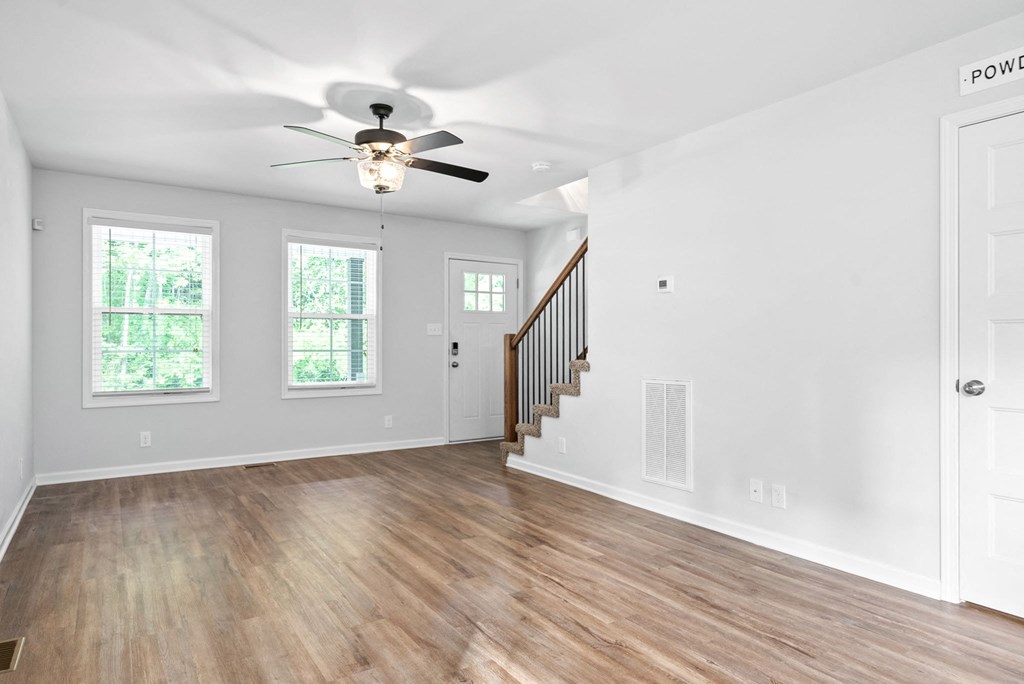 an empty living room with white walls and a ceiling fan
