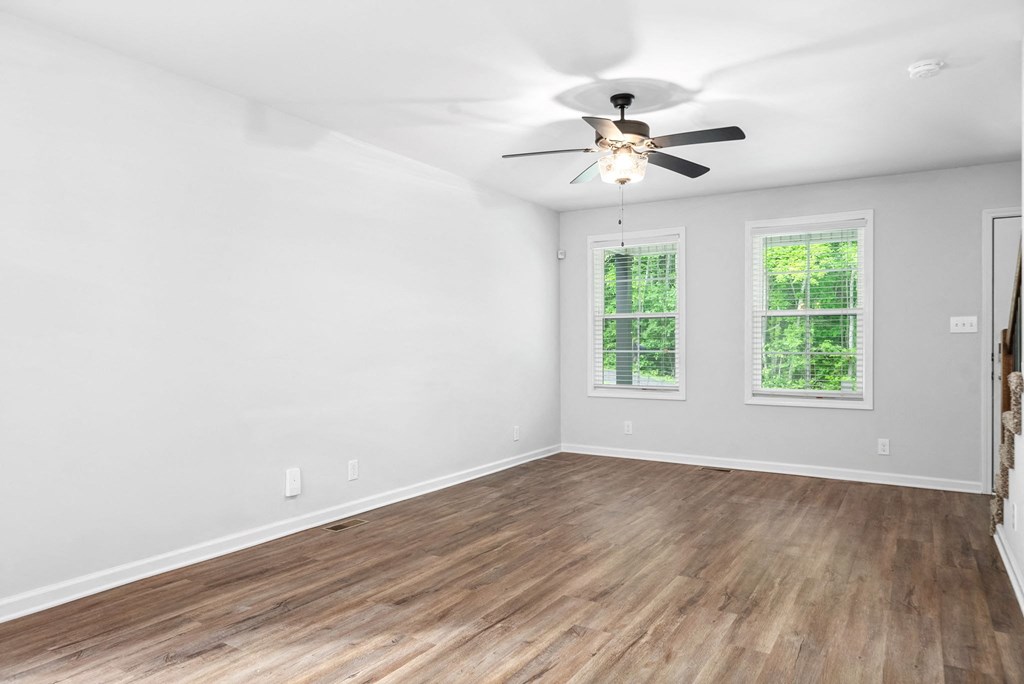 an empty living room with white walls and a ceiling fan