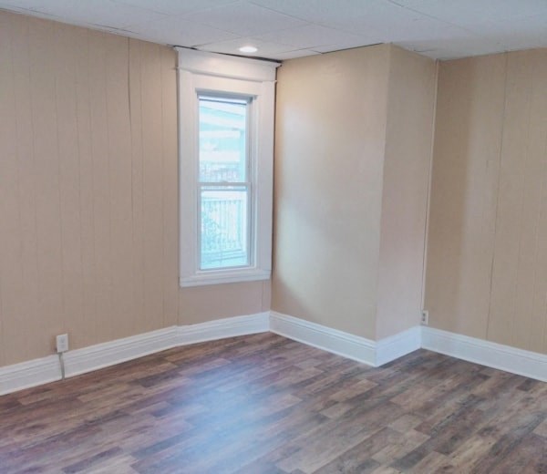 an empty living room with wooden floors and a window
