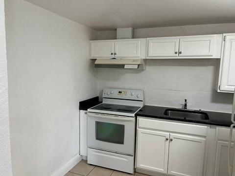 a kitchen with a stove and white cabinets