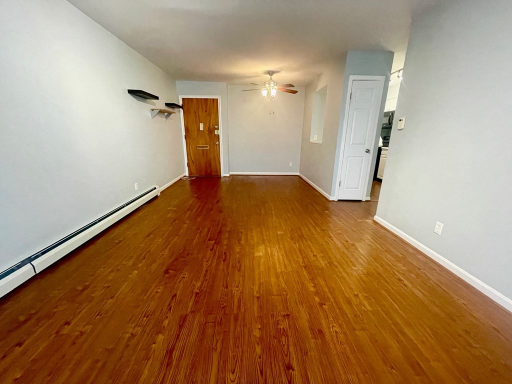 an empty living room with wood flooring and white walls