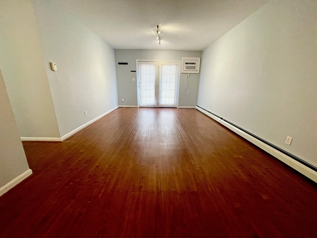 an empty living room with wood floors and white walls