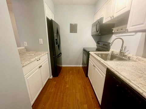 a kitchen with white cabinets and stainless steel appliances and a wood floor