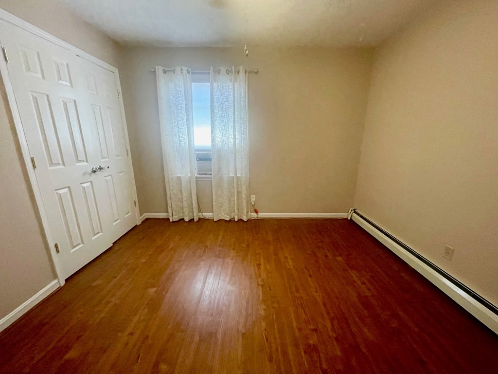 an empty living room with wood floors and white walls