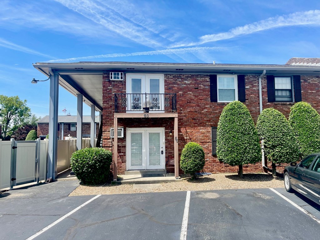an empty parking lot in front of a brick house
