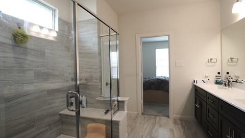 a bathroom with a shower and a sink and a bedroom
