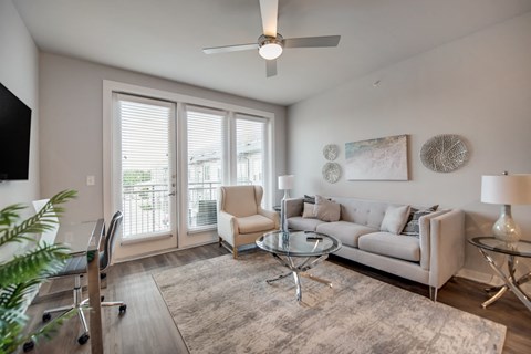 a living room with a couch and a chair and a ceiling fan