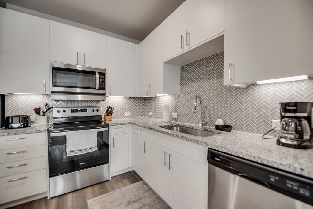 a kitchen with white cabinets and granite counter tops and stainless steel appliances
