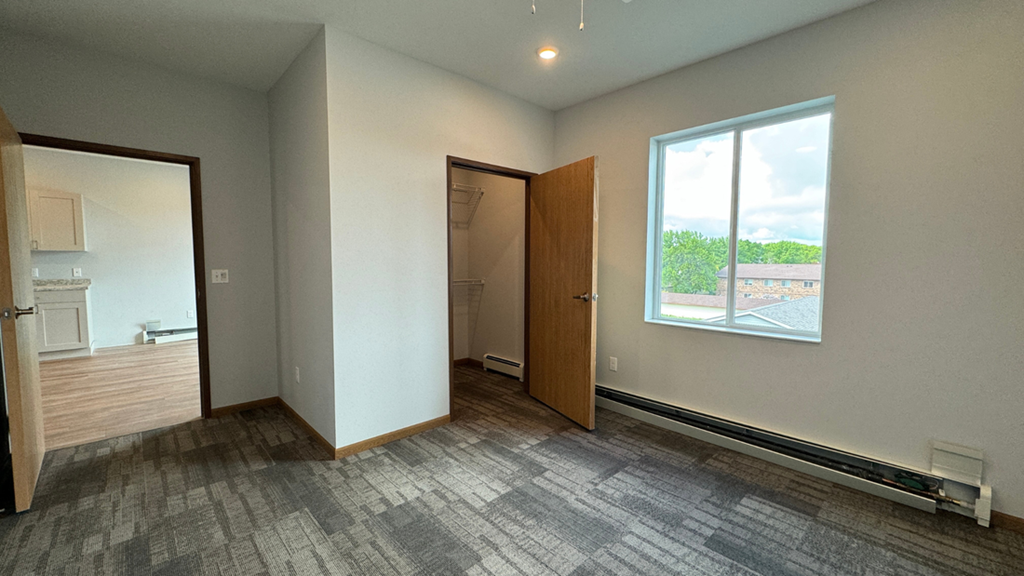 an empty living room with a window and a door to a bathroom