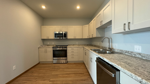 an empty kitchen with white cabinets and granite counter tops