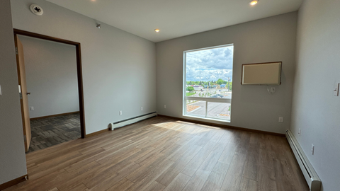 an empty living room with wood floors and a large window