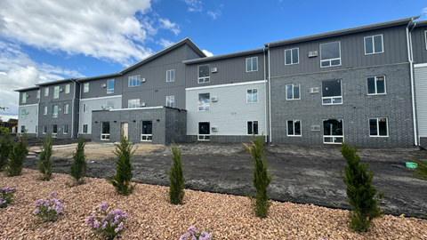 an apartment building with gravel and plants in front of it