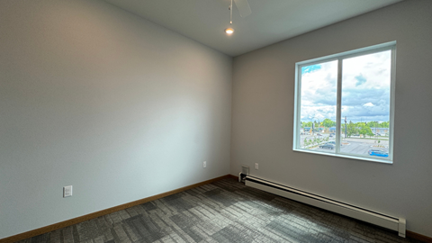 an empty living room with a large window and wood flooring