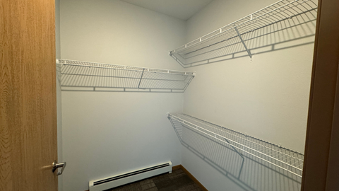 a walk in closet with two white shelves and a door