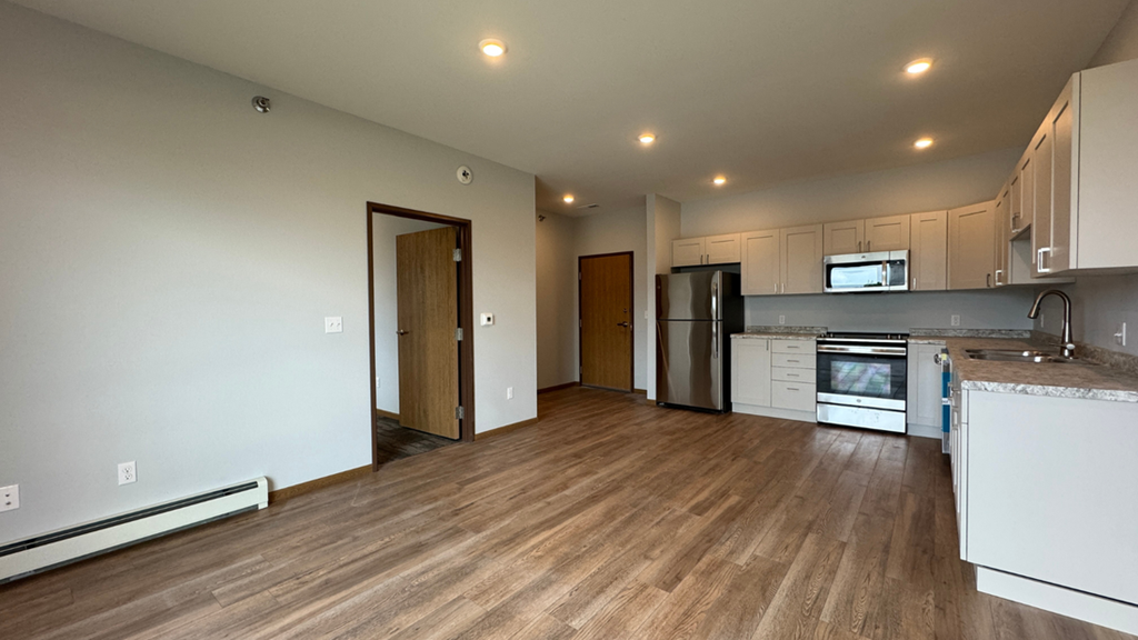 a kitchen and living room with a wood floor and white cabinets