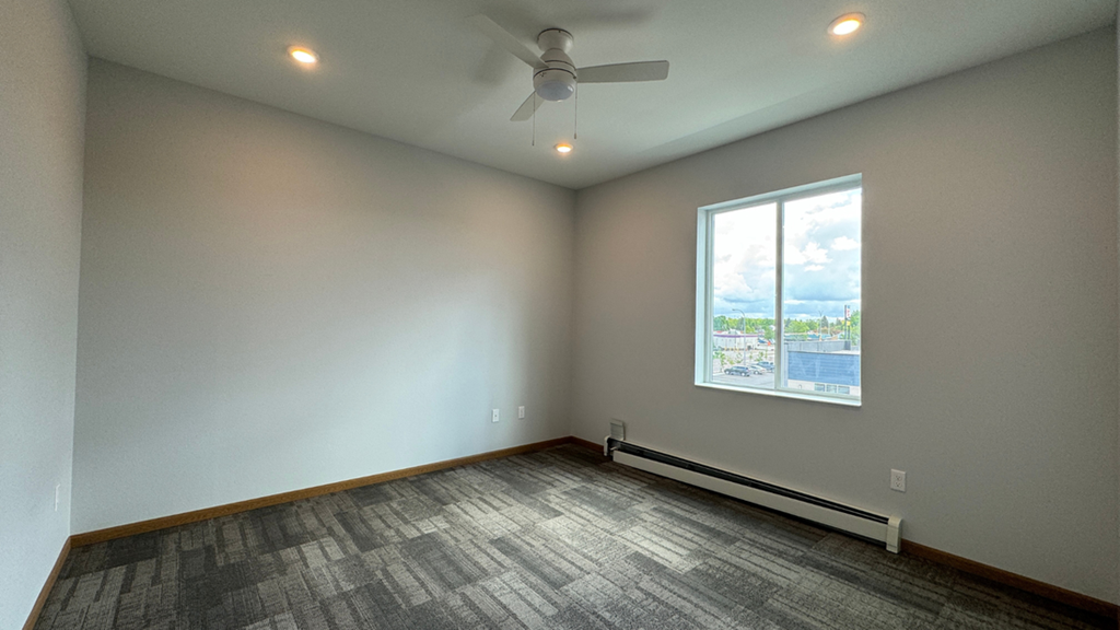 an empty living room with a ceiling fan and a window