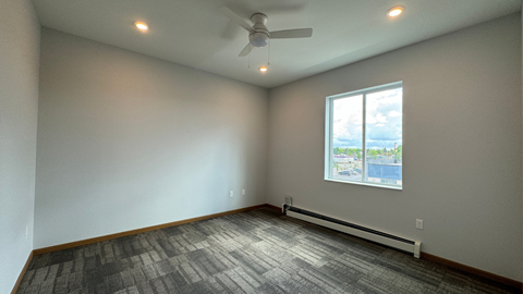 an empty living room with a ceiling fan and a window