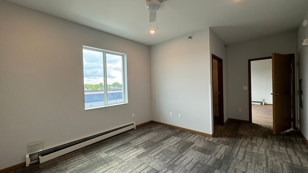 an empty living room with a large window and wood flooring