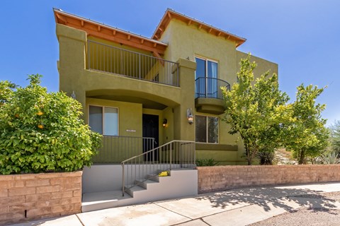 the front of a house with a staircase and a balcony