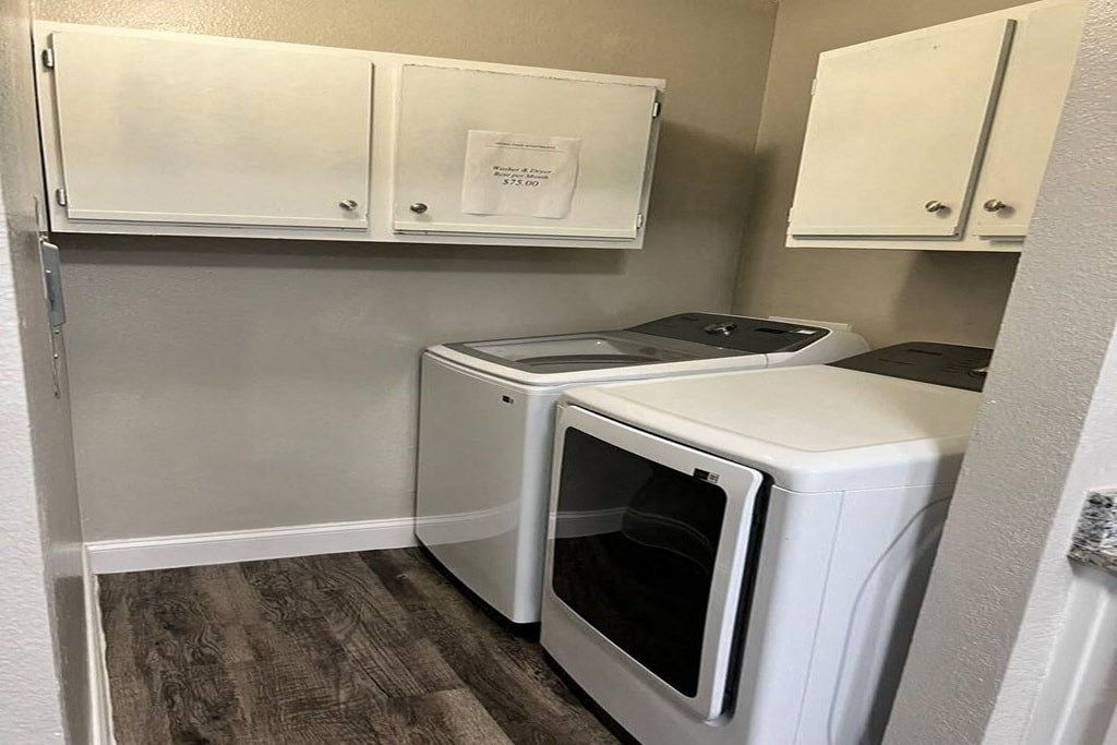 a white washer and dryer in a small room with white cabinets