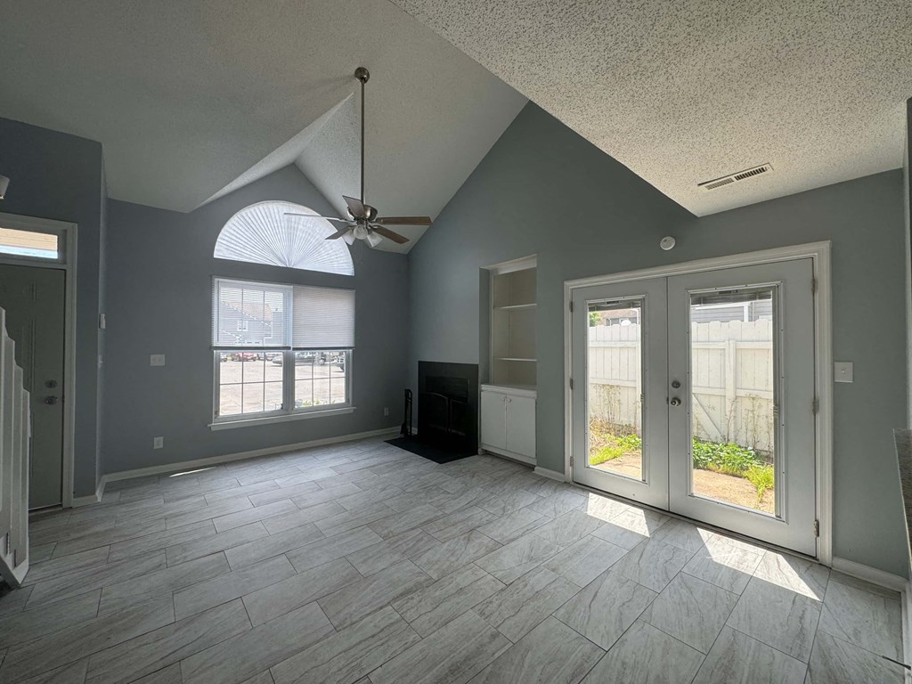 a living room with a ceiling fan and a glass door