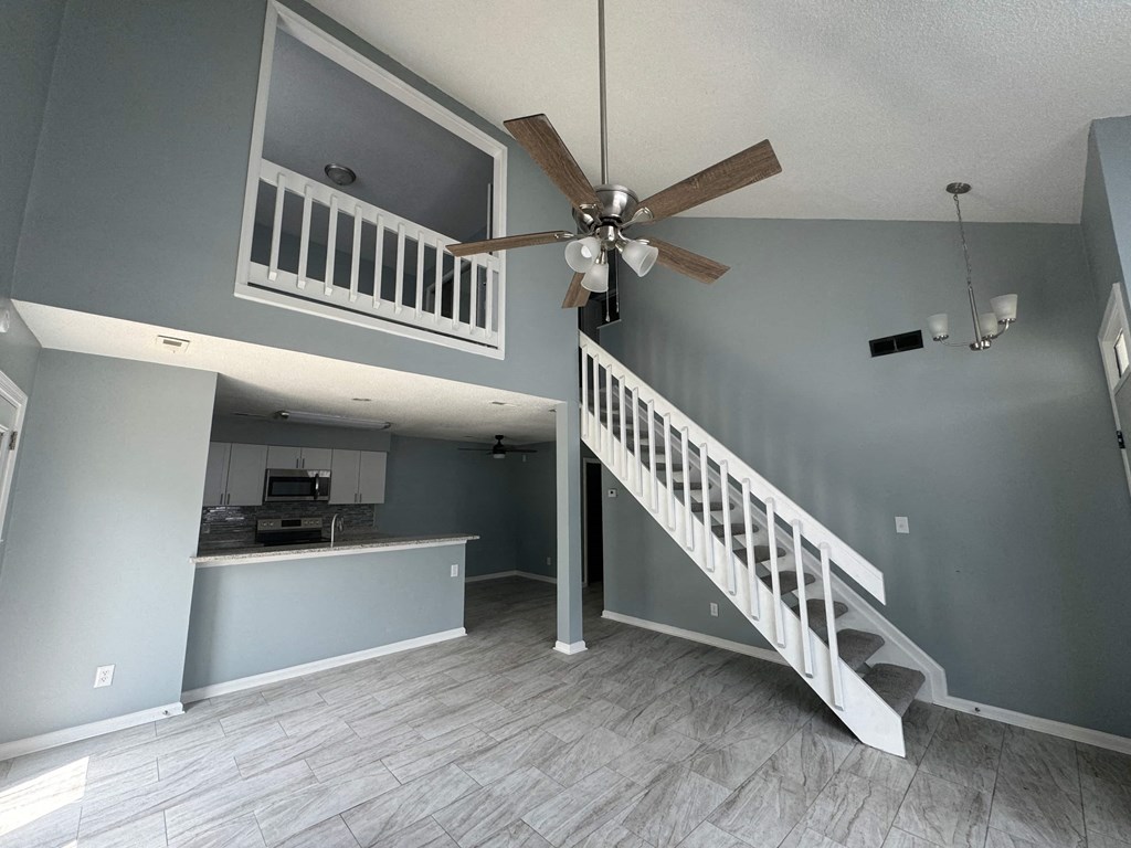 a living room with a staircase and a ceiling fan